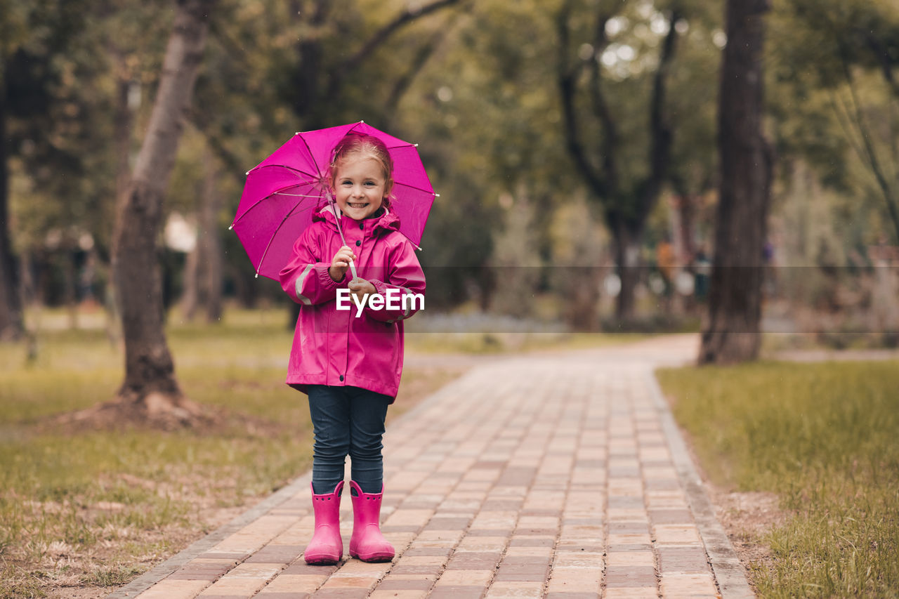 Full length of girl with umbrella standing in park