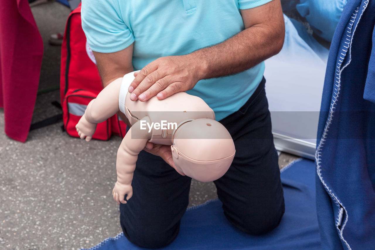 Midsection of man holding cpr dummy