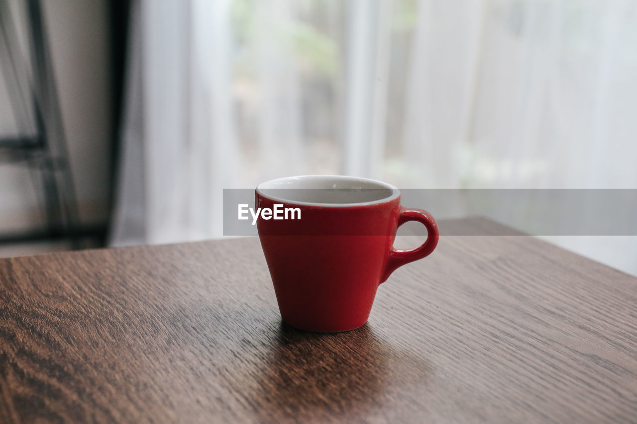 CLOSE-UP OF COFFEE CUP ON TABLE AGAINST BLURRED BACKGROUND