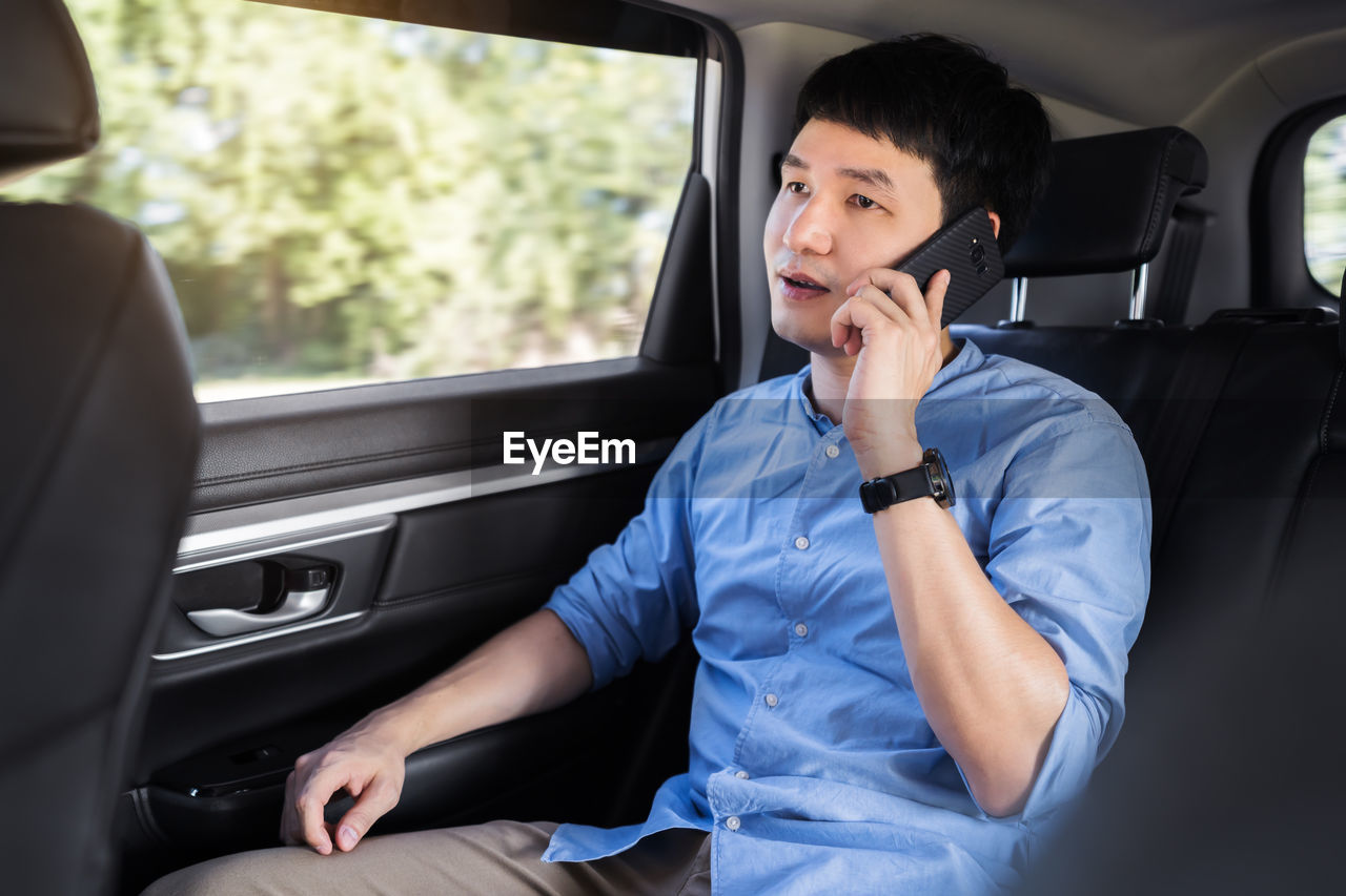 portrait of young man using mobile phone while sitting in car