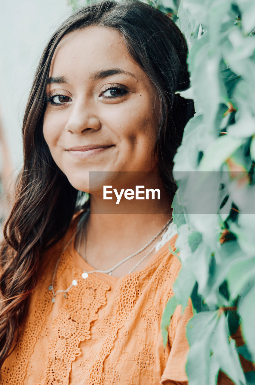 Portrait of smiling woman by plants outdoors