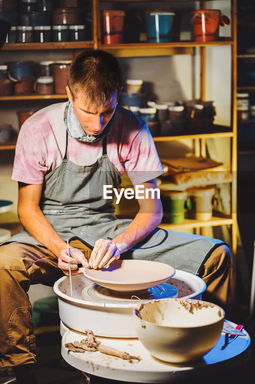 Potter making pot while sitting in pottery workshop