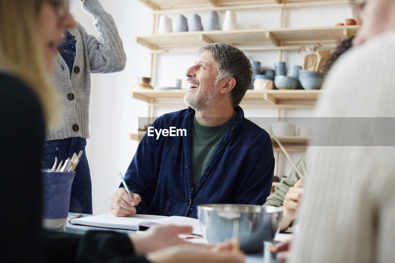 Smiling mature male student talking with female instructor in art studio