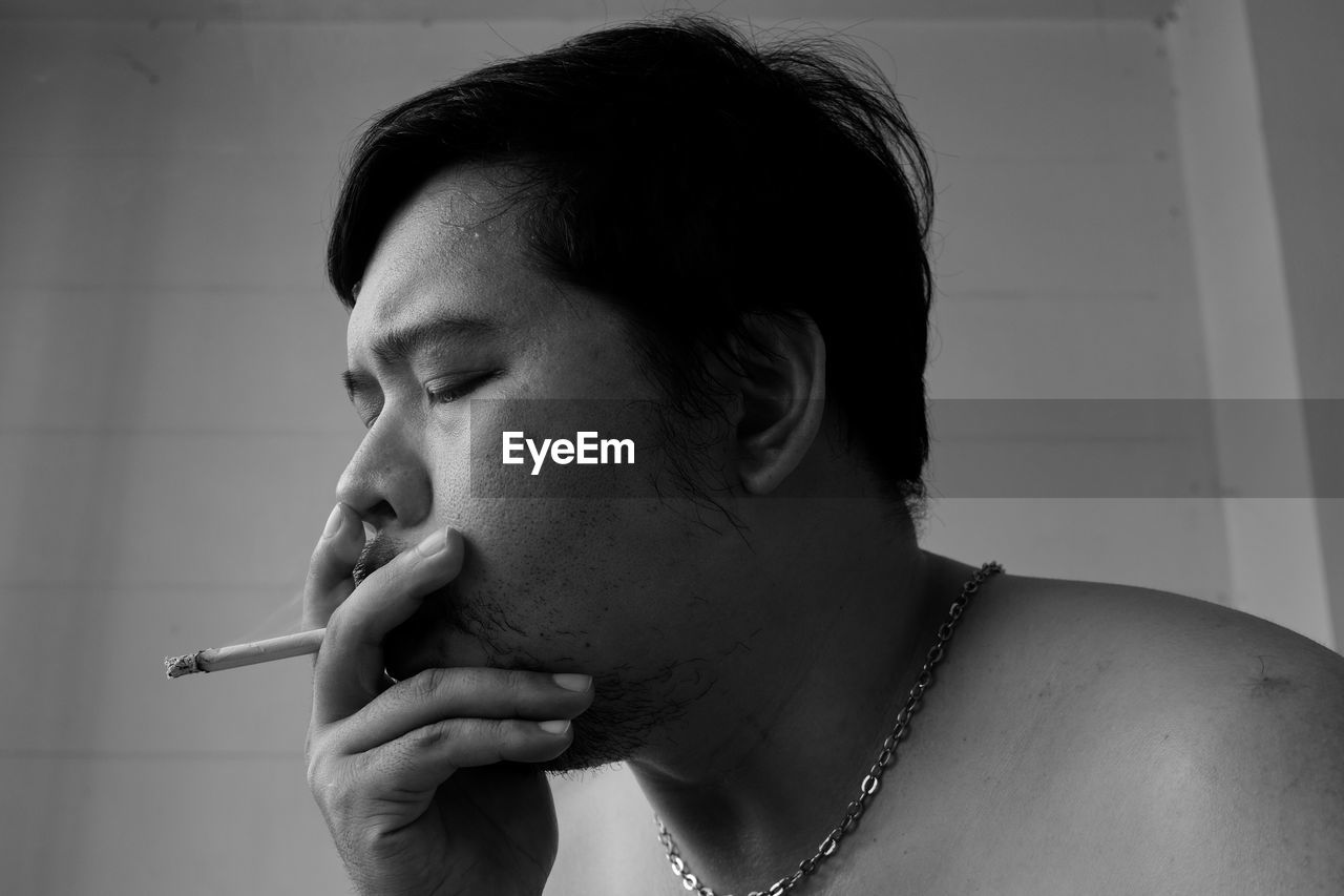 CLOSE-UP PORTRAIT OF A MAN SMOKING CIGARETTE