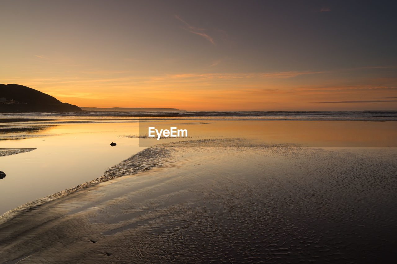 Scenic view of beach against sky during sunset