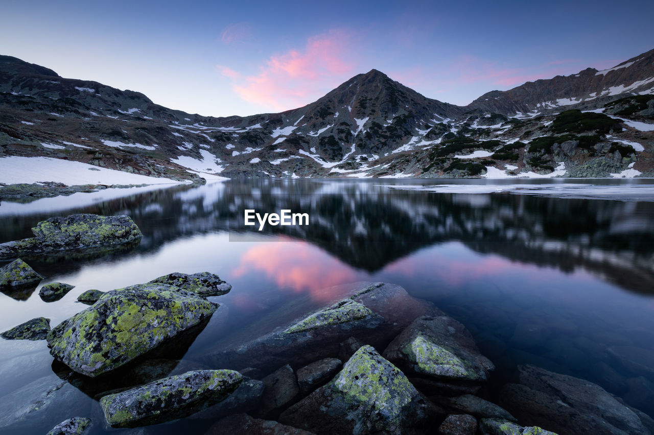 Scenic view of lake and snowcapped mountains against sky in retezat mountains 