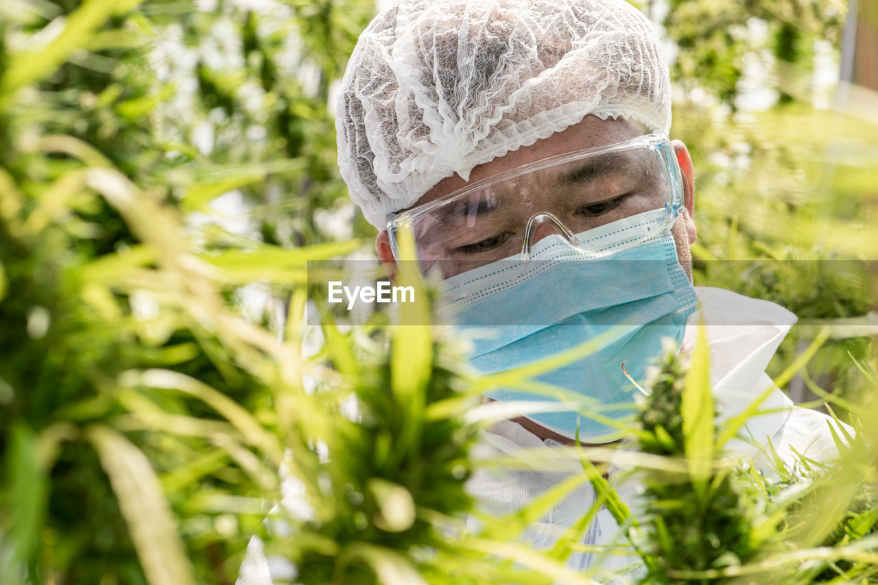 PORTRAIT OF A MAN HOLDING PLANT IN FIELD