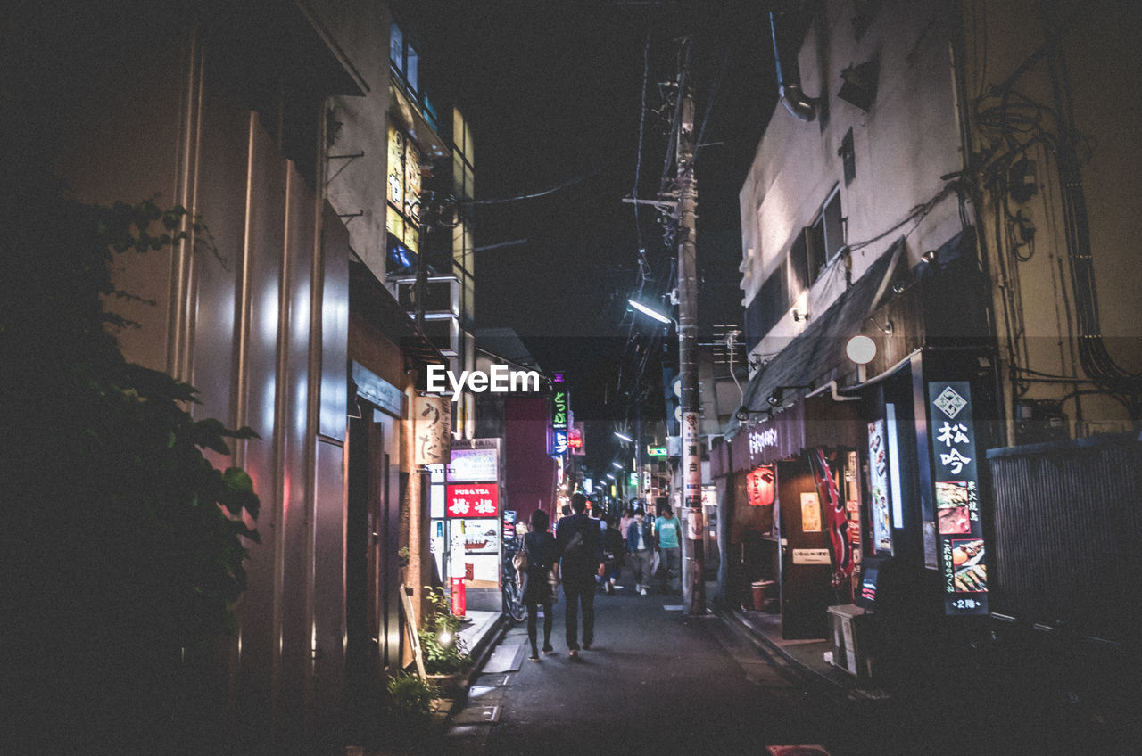 PEOPLE WALKING ON STREET IN CITY AT NIGHT