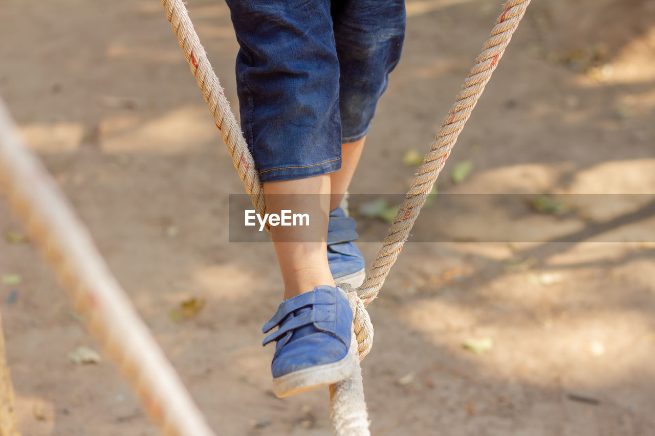 Low section of child walking on rope in playground