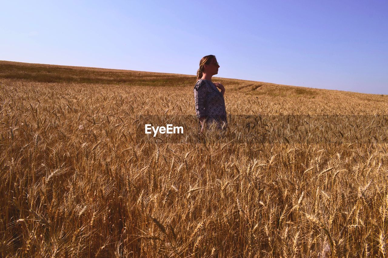 Side view of woman standing on field against clear sky