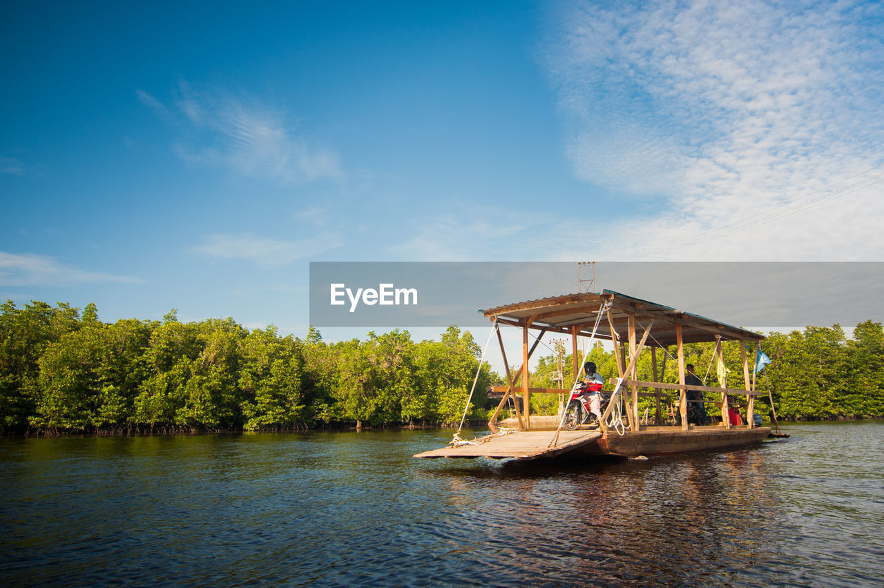 MAN SAILING ON RIVER AGAINST SKY