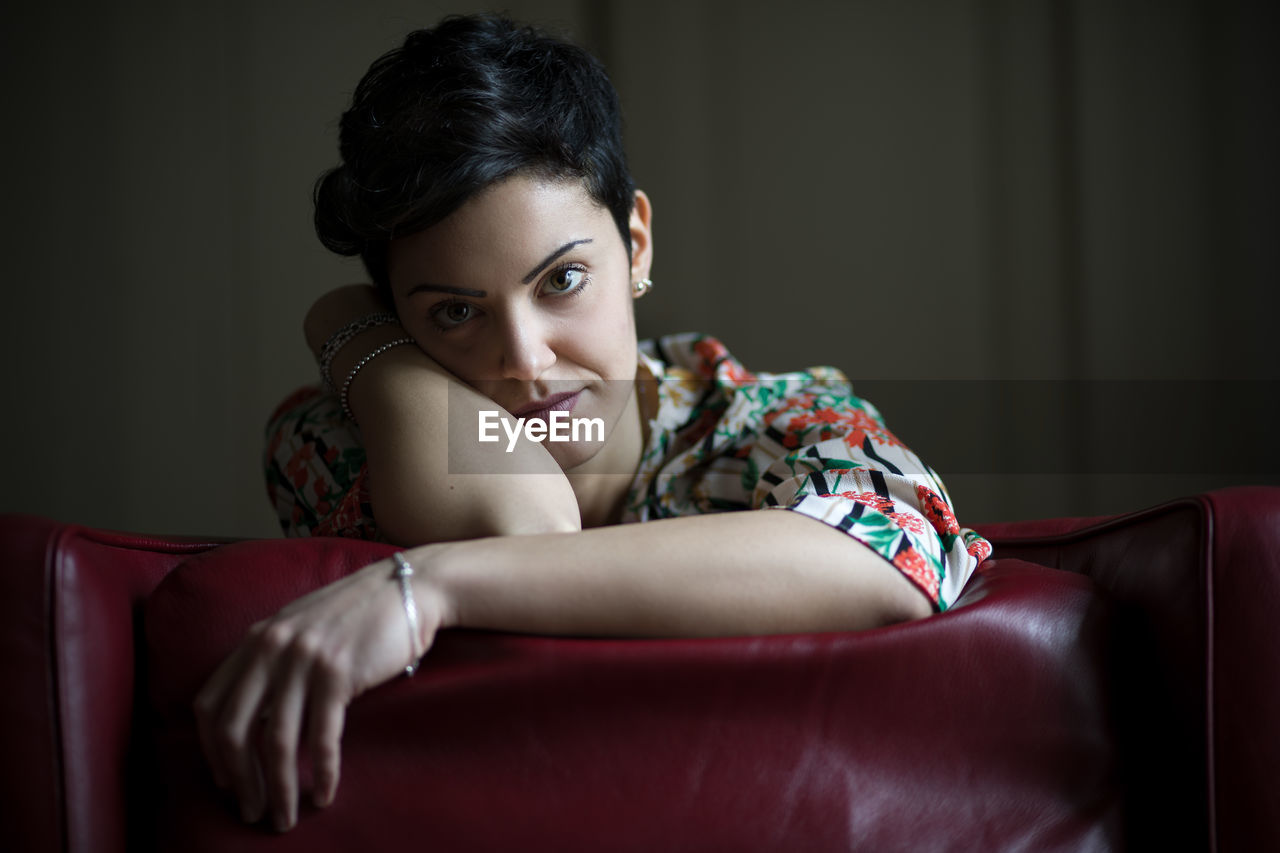 Portrait of smiling young woman sitting on chair at home