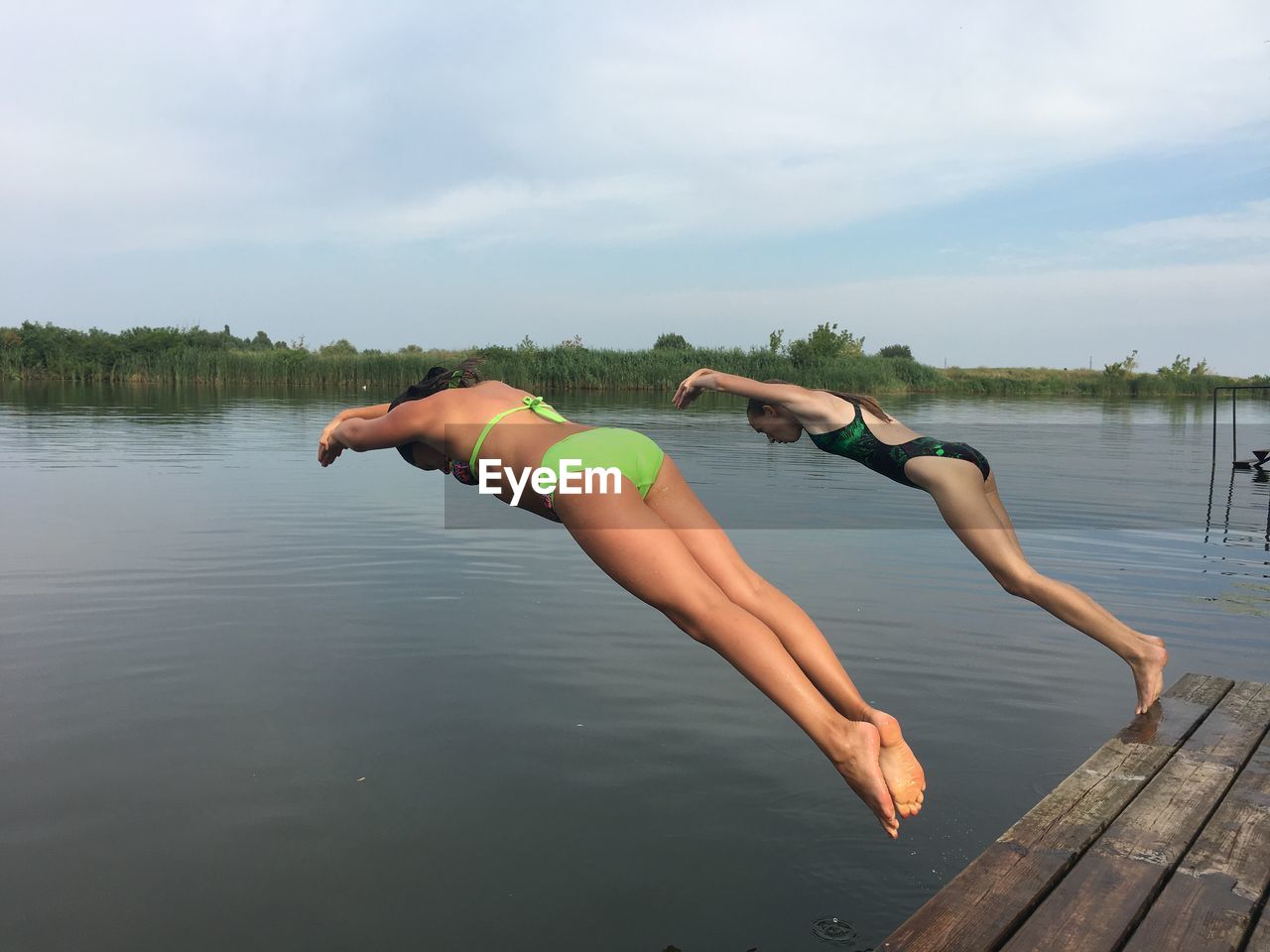 WOMAN JUMPING INTO LAKE AGAINST SKY