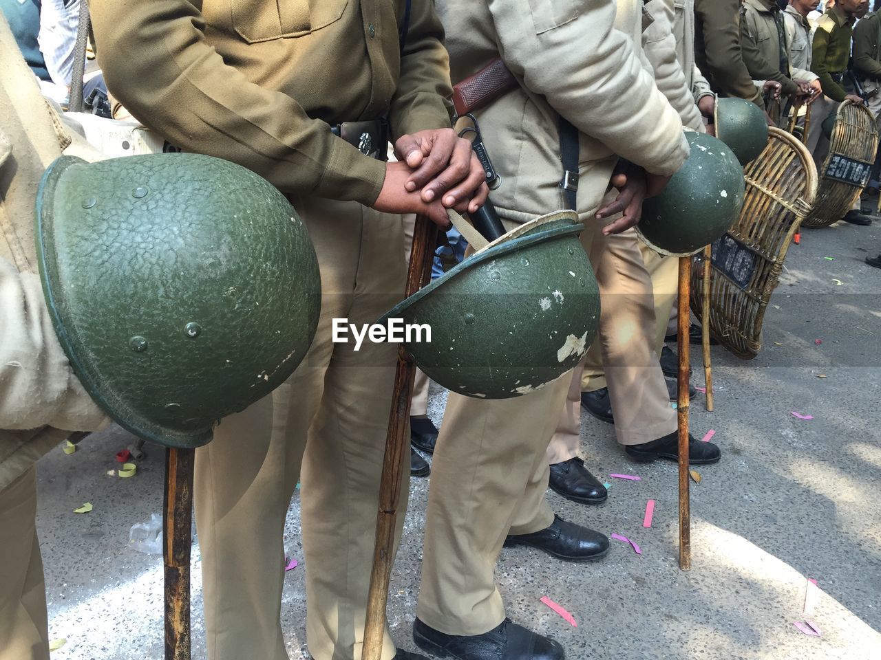 Low section of police holding helmets while standing on street