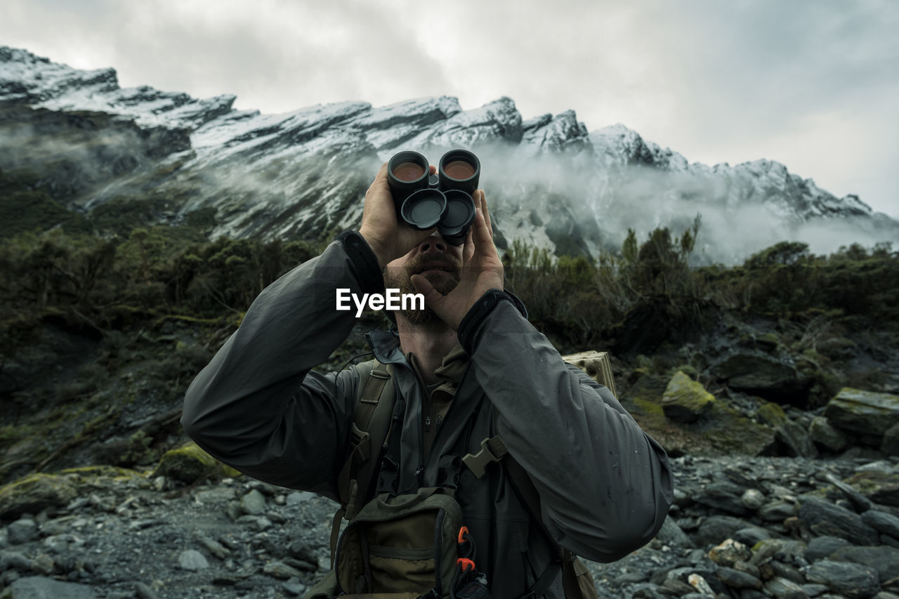 Hunter in mountains looking through monocular