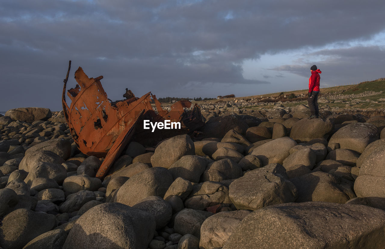 rock, sky, cloud, one person, nature, sea, land, coast, sand, full length, adult, landscape, standing, natural environment, beach, environment, terrain, men, outdoors, scenics - nature, leisure activity, beauty in nature, geology, lifestyles, activity, day, non-urban scene