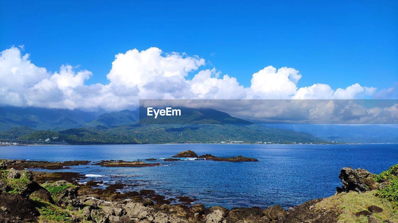 Scenic view of sea and mountains against blue sky