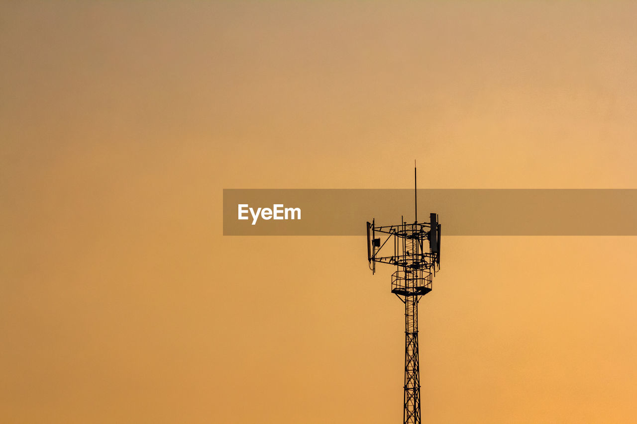 low angle view of electricity pylon against orange sky