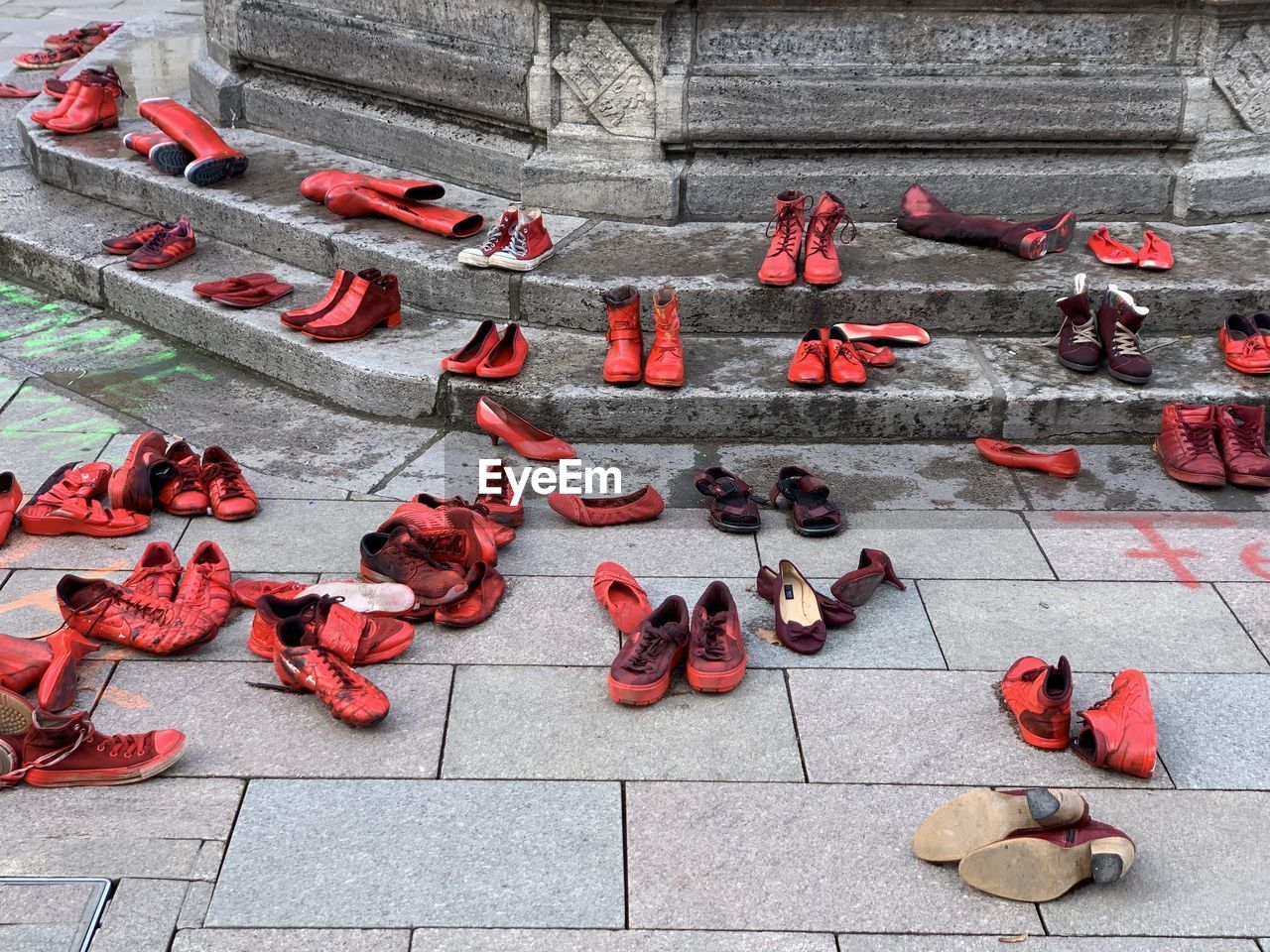 High angle view of red shoes in public on footpath in city, artistic