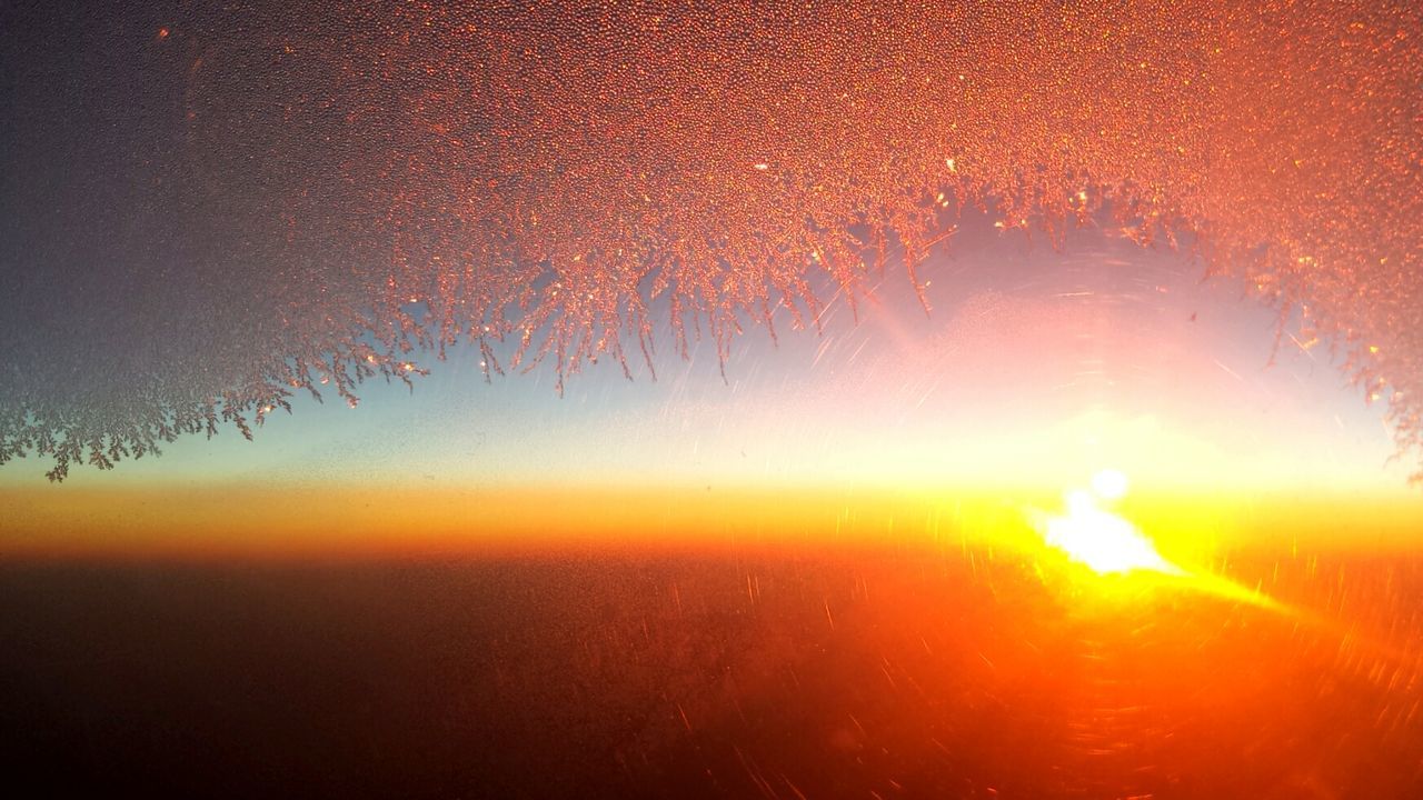 Scenic view of sunset through airplane window covered with snowflakes