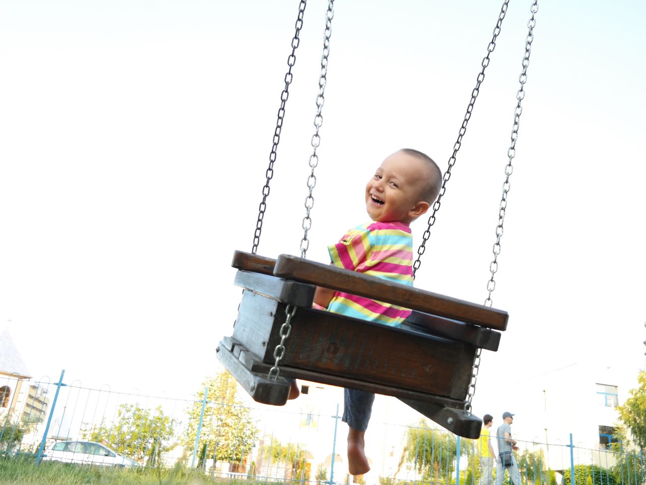 Portrait of happy boy enjoying in swing at park against clear sky