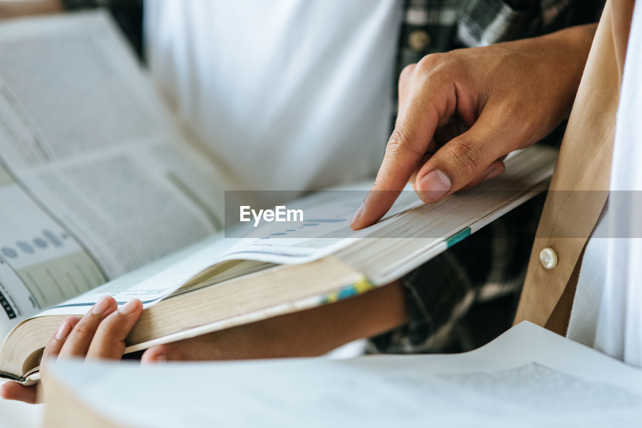 Midsection of students reading book