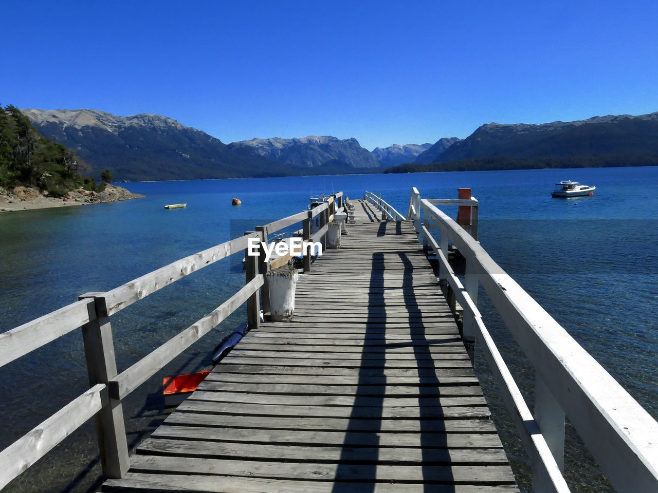 Pier on sea against clear blue sky