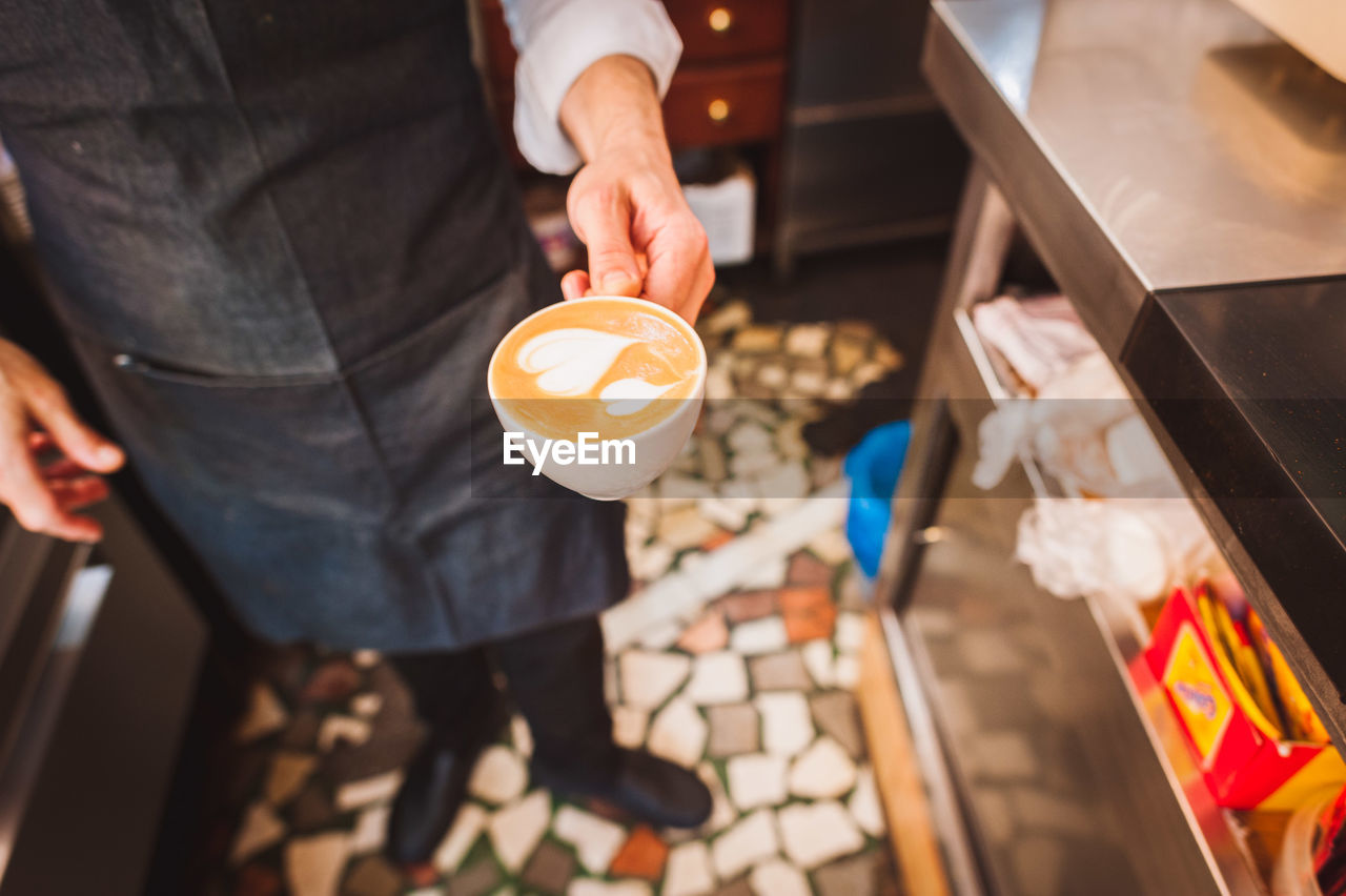 Close-up of barista holding coffee cup at cafe