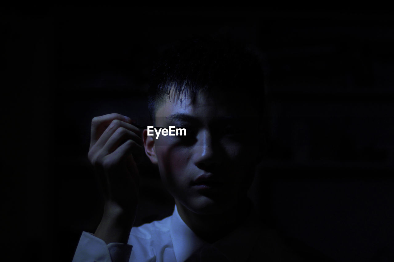 Man applying mascara in darkroom