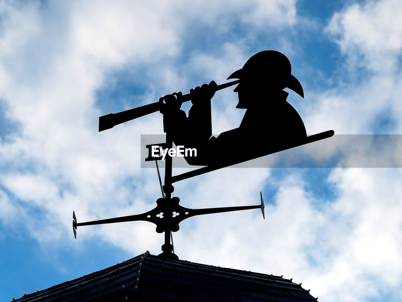 A weather vane with person looking through a telescope