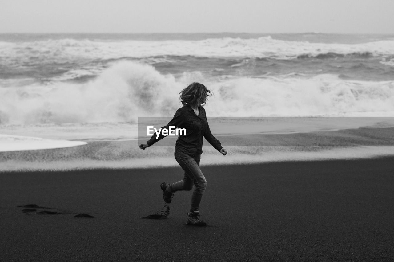 Tourist running along reynisfjara beach monochrome scenic photography