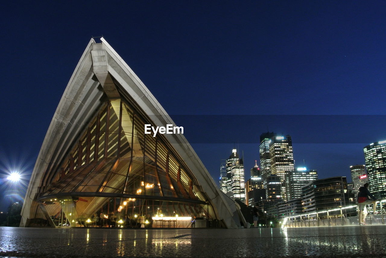 LOW ANGLE VIEW OF ILLUMINATED CITY AT NIGHT