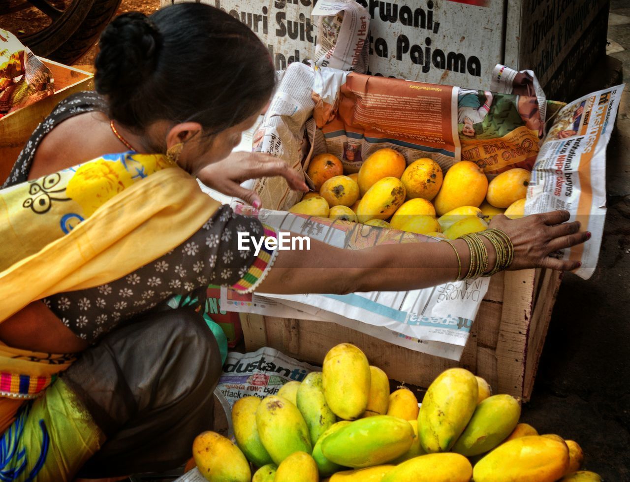 High angle view of vendor with mangos in market