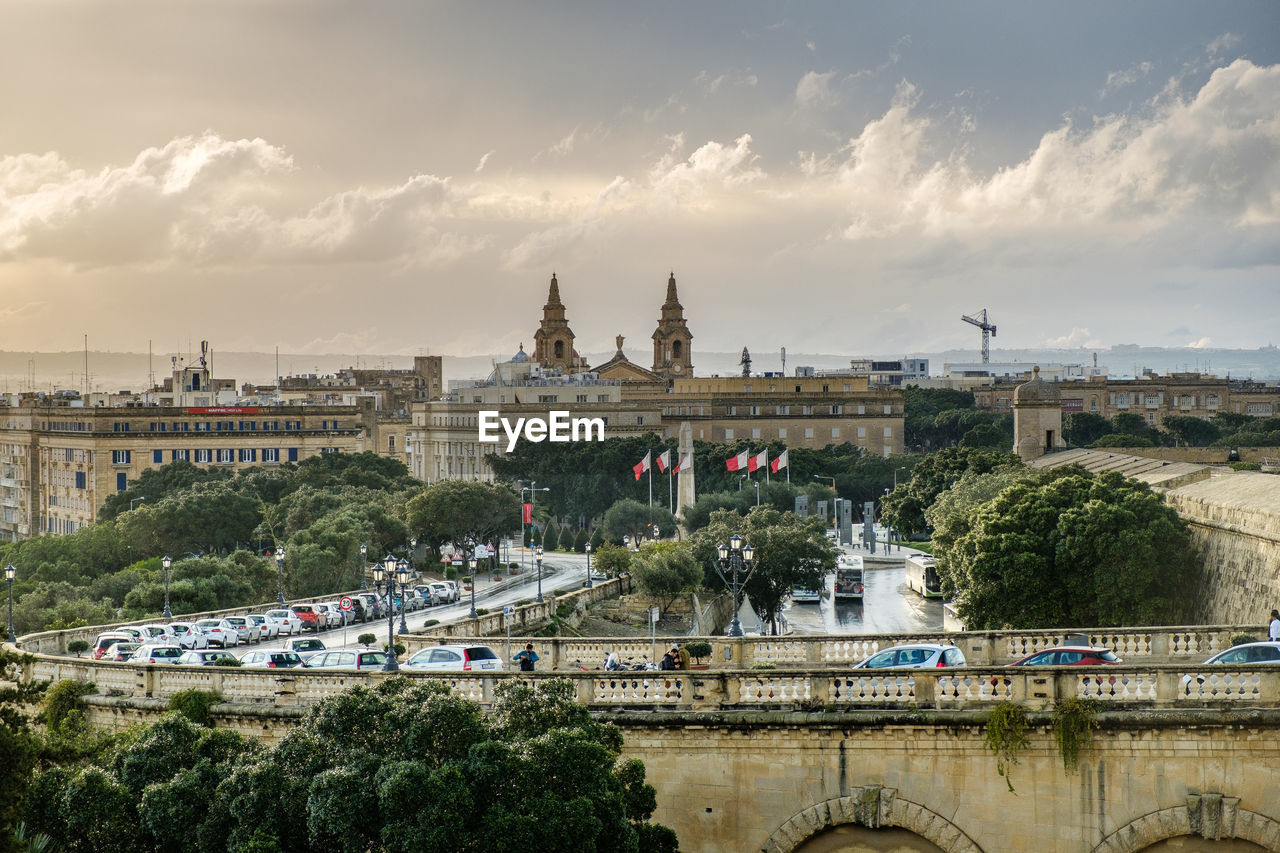 View of trees and buildings against cloudy sky