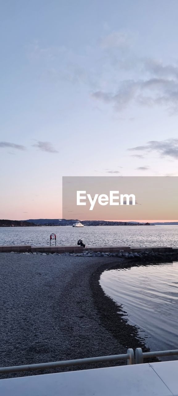 SCENIC VIEW OF BEACH AGAINST SKY AT SUNSET