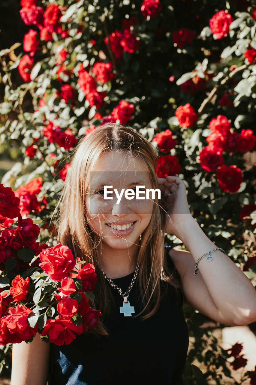 Portrait of smiling young woman by flowering tree