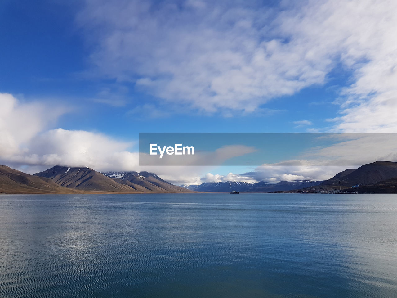 Scenic view of sea by snowcapped mountains against sky