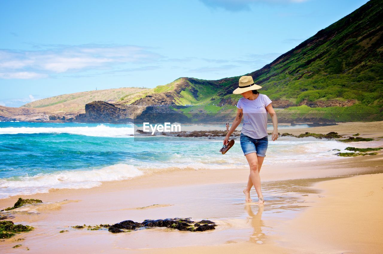 Full length of woman in hat walking on beach
