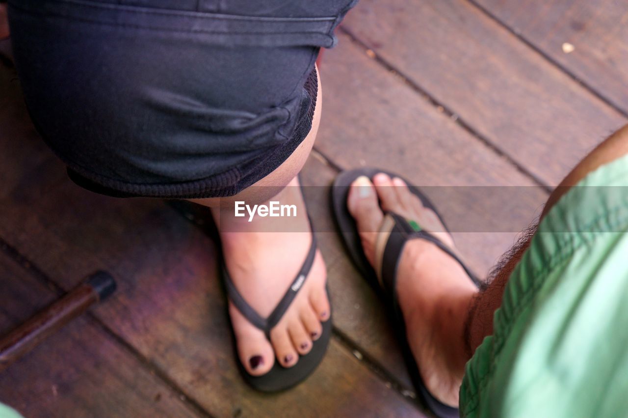 Low section of people wearing slippers on boardwalk