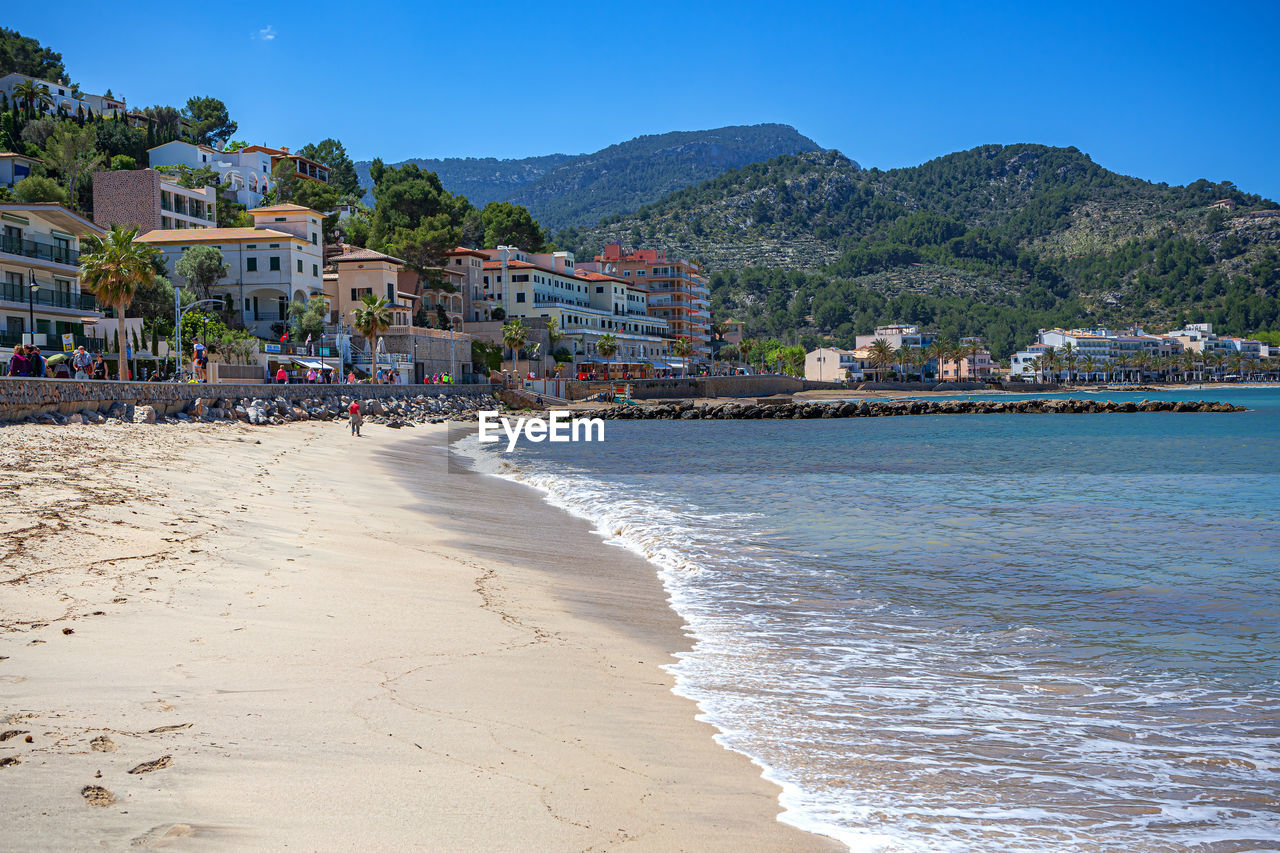 land, beach, water, sea, body of water, architecture, sky, nature, travel destinations, sand, vacation, building exterior, coast, built structure, travel, city, building, coastline, holiday, trip, tourism, shore, mountain, scenics - nature, environment, clear sky, sunny, beauty in nature, landscape, summer, blue, house, tree, water's edge, outdoors, residential district, tranquility, ocean, town, cityscape, sunlight, wave, seascape, plant, motion, idyllic, tourist resort, bay, no people, day, nautical vessel, tranquil scene, sports, relaxation, transportation, water sports, bay of water, hut, island, tropical climate