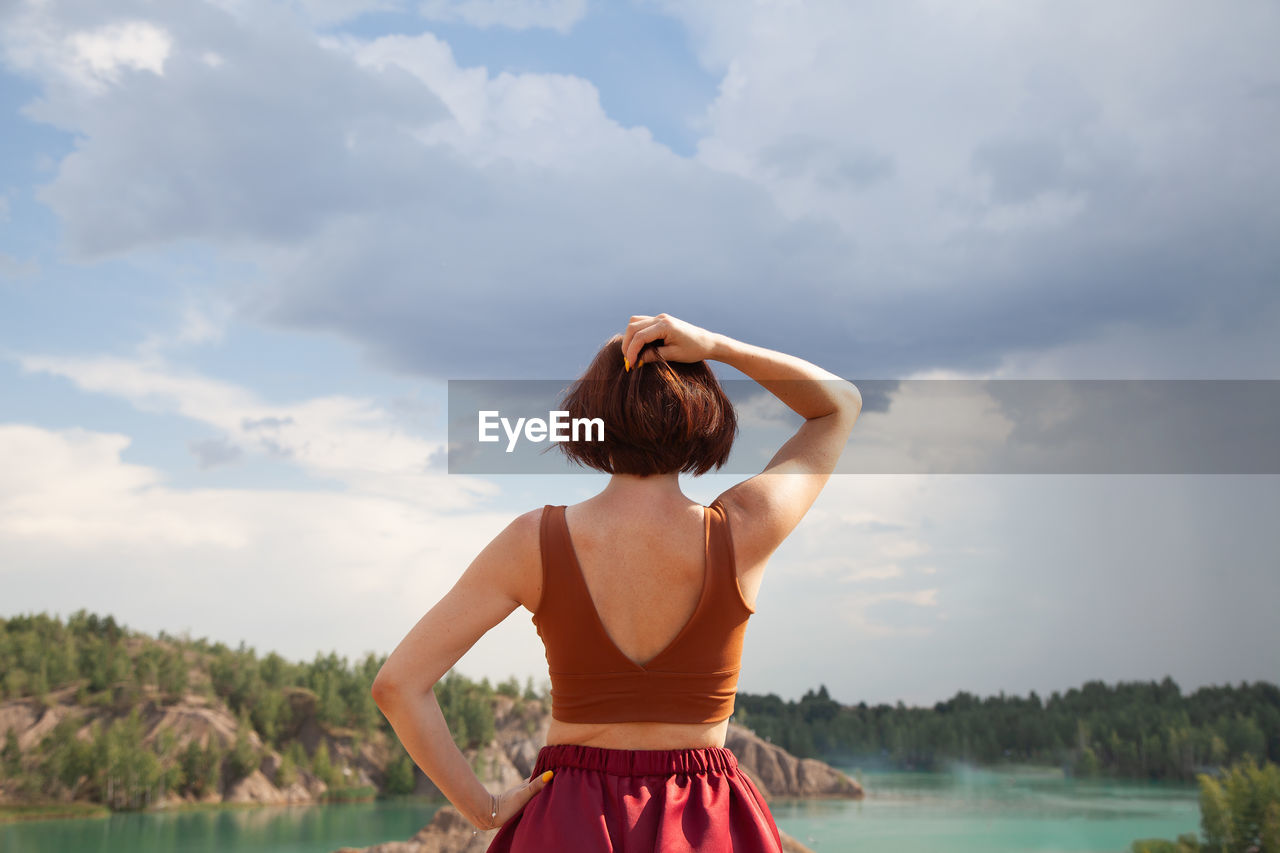 Rear view of woman standing against lake