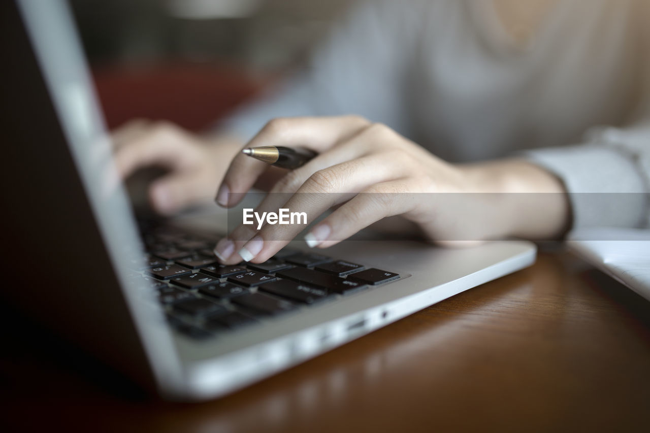 Midsection of woman using laptop on table