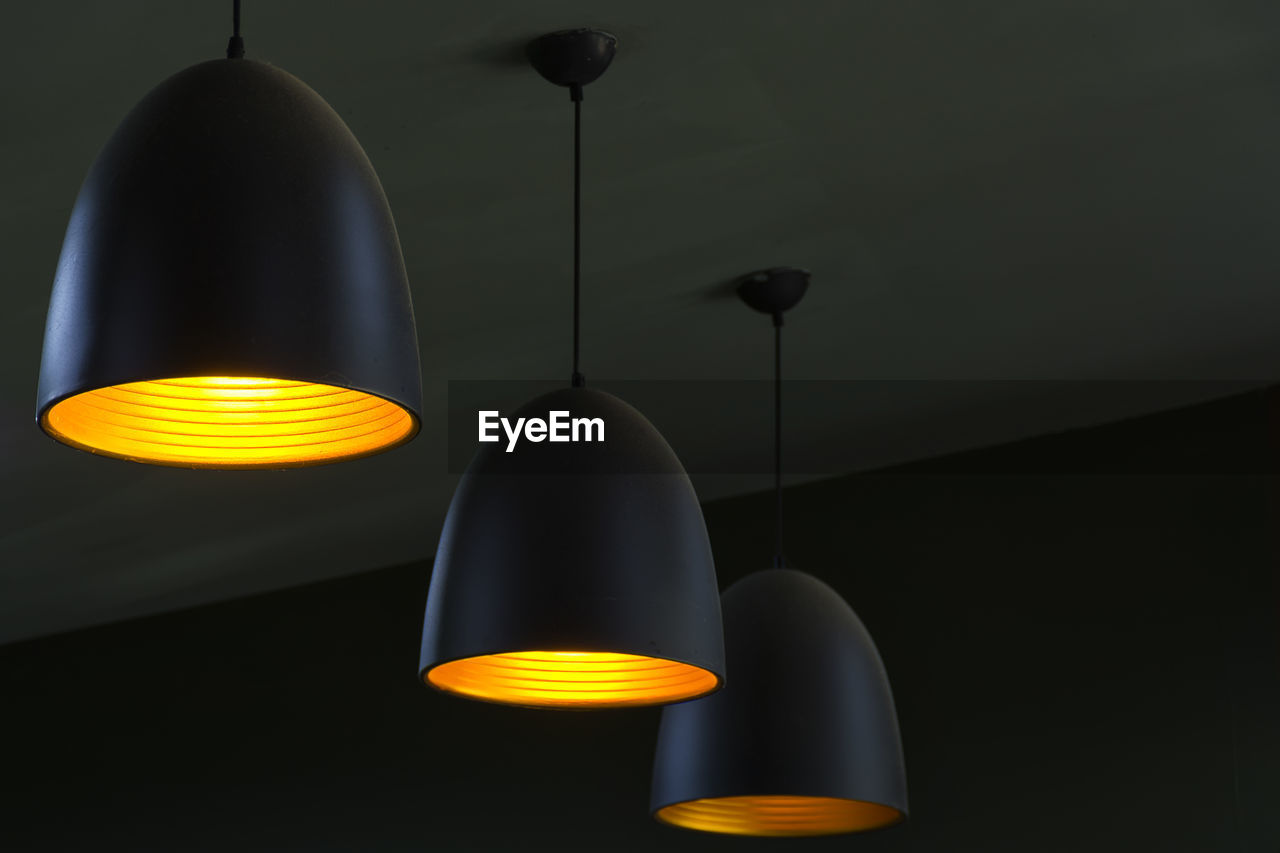 Low angle view of illuminated pendant lights hanging from ceiling