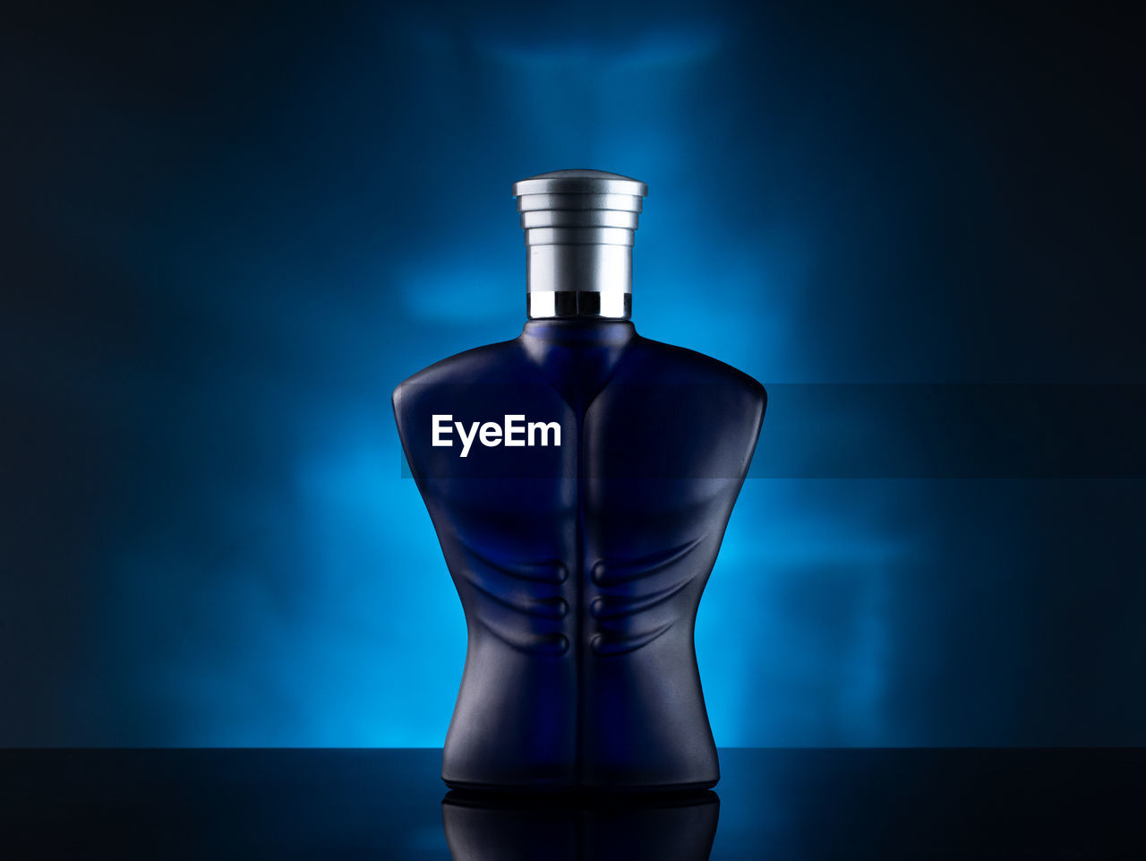 Close-up of perfume bottle on table against blue background