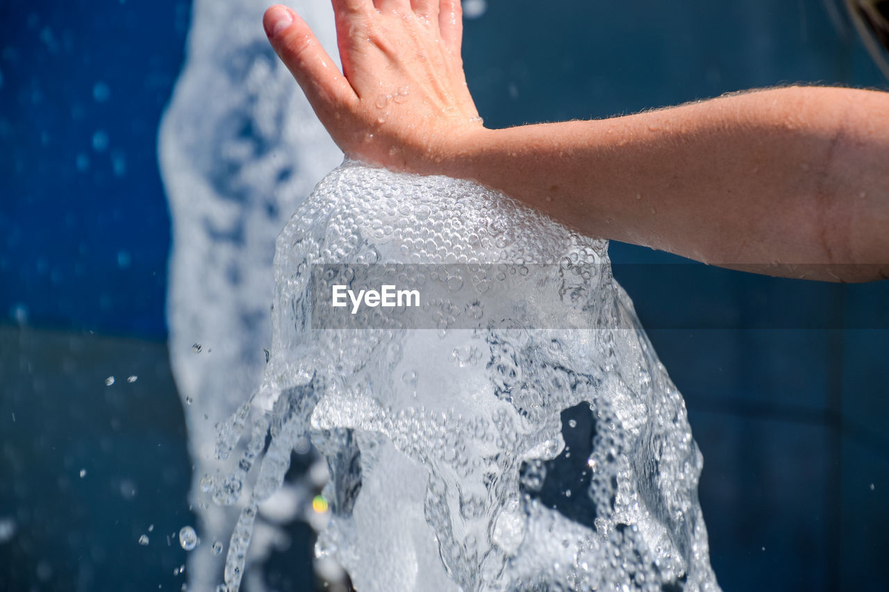 Cropped hand touching water in fountain