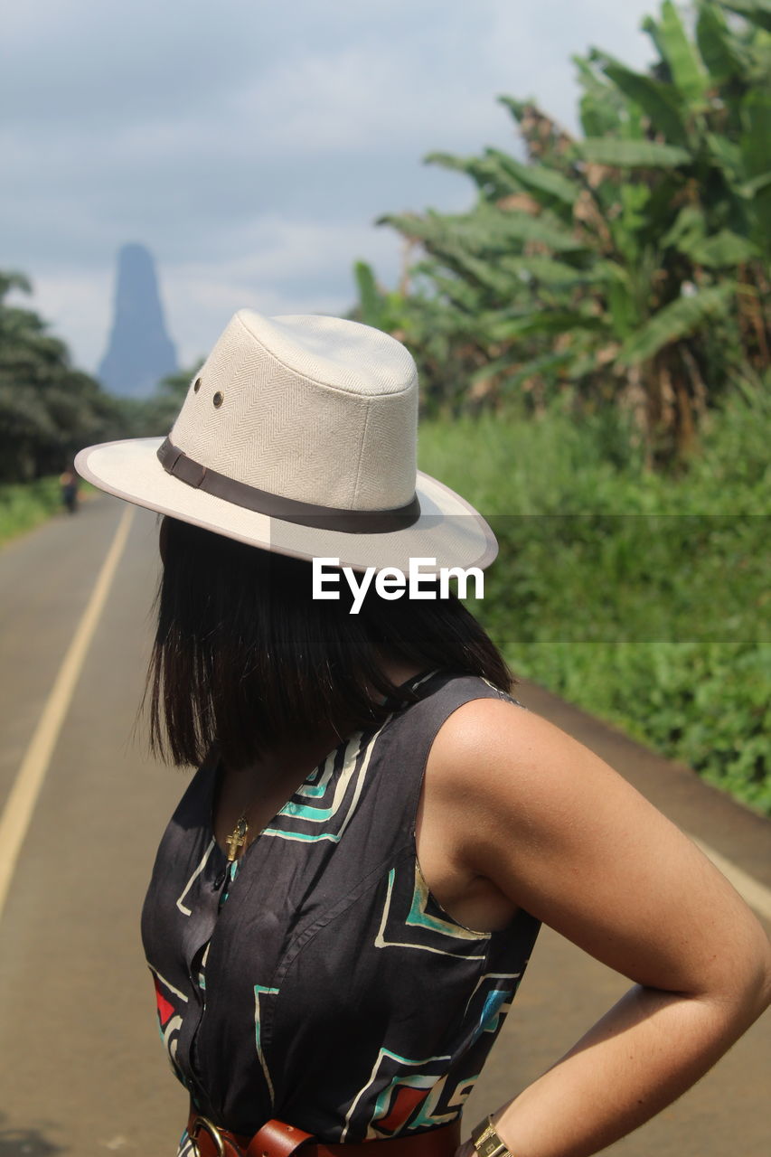 Rear view of woman with hat standing against plants