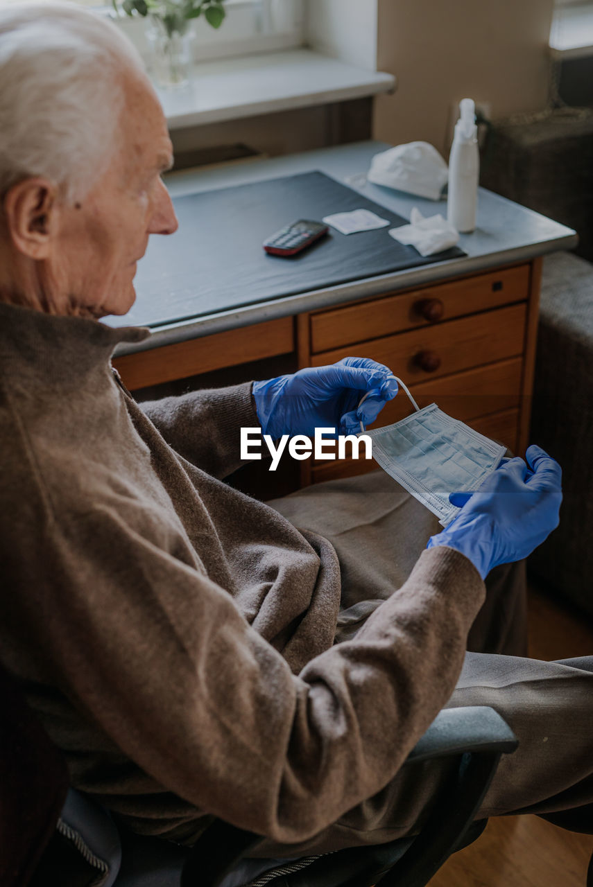 Senior man holding surgical mask at home