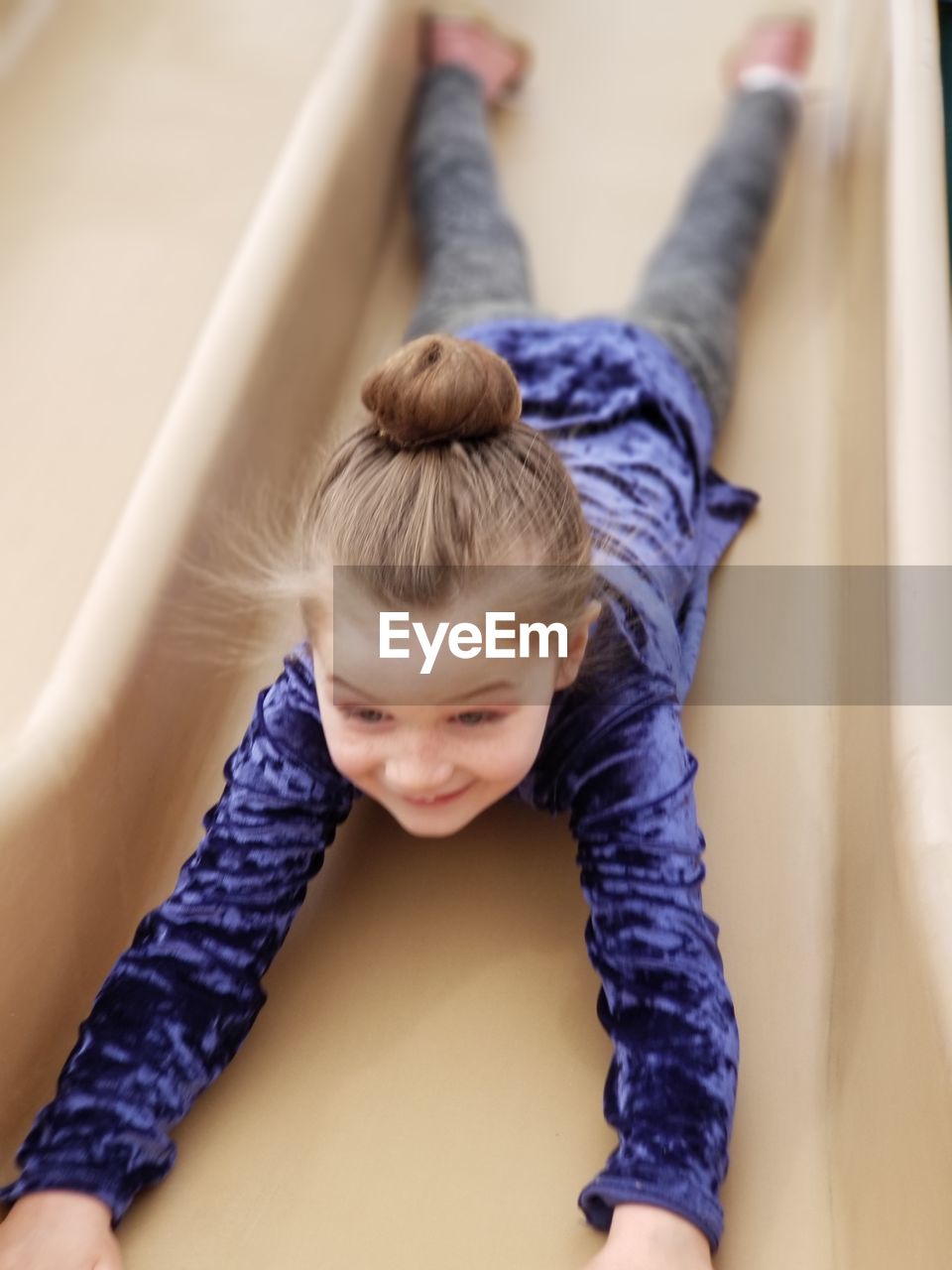 High angle view of playful girl lying on slide