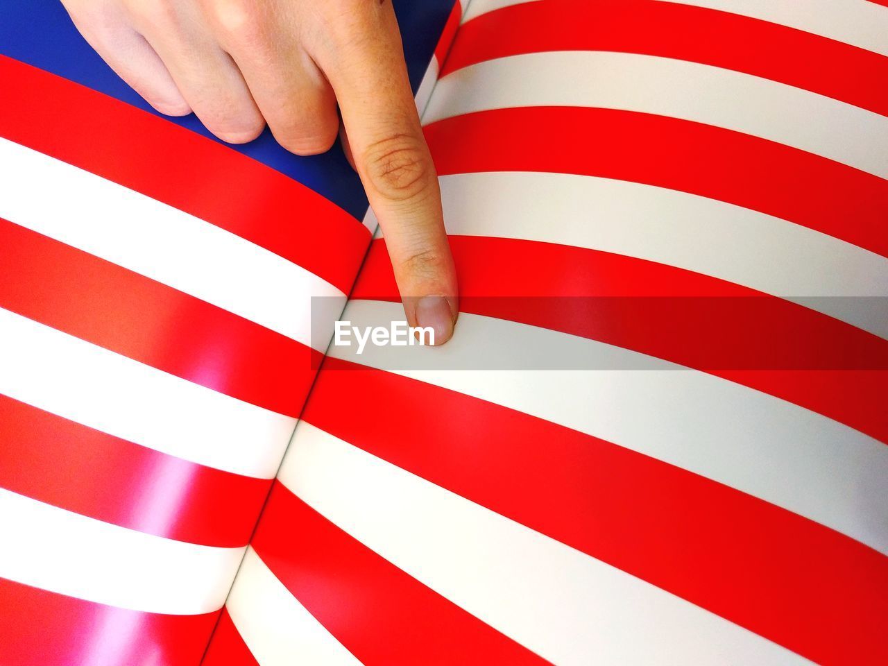 Close-up of hand pointing to american flag print