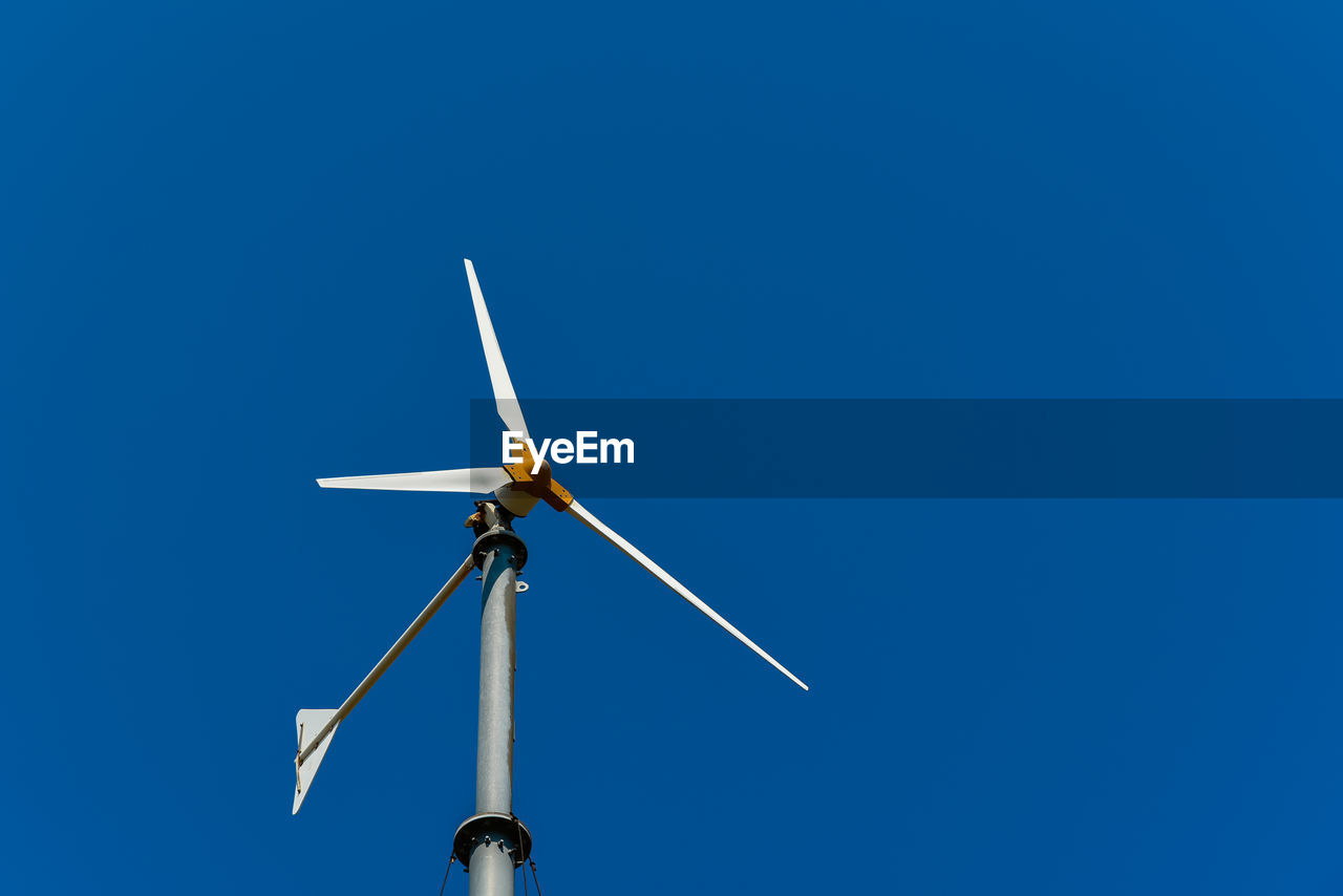 Low angle view of windmill against clear blue sky